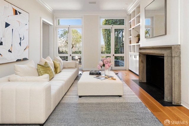living area featuring baseboards, a premium fireplace, ornamental molding, french doors, and wood finished floors