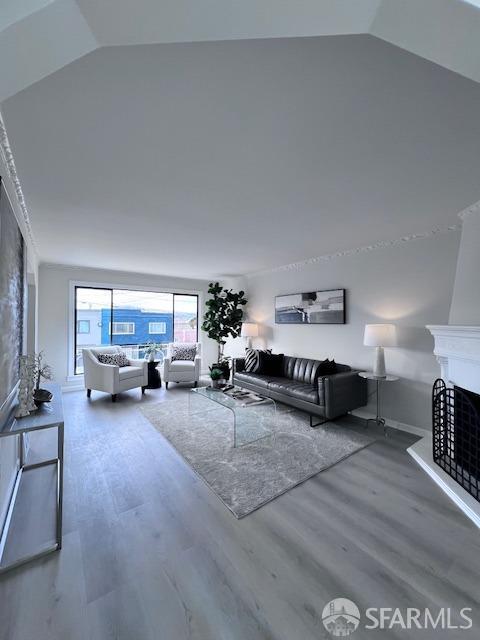 living area featuring lofted ceiling, a fireplace, and wood finished floors