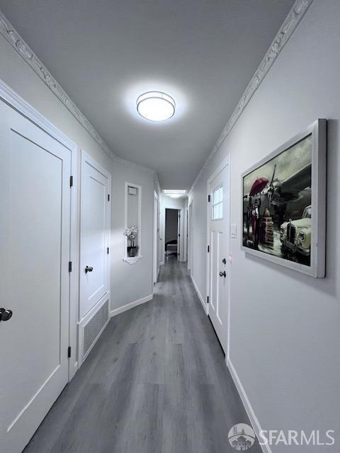 hallway featuring crown molding, dark wood finished floors, and baseboards