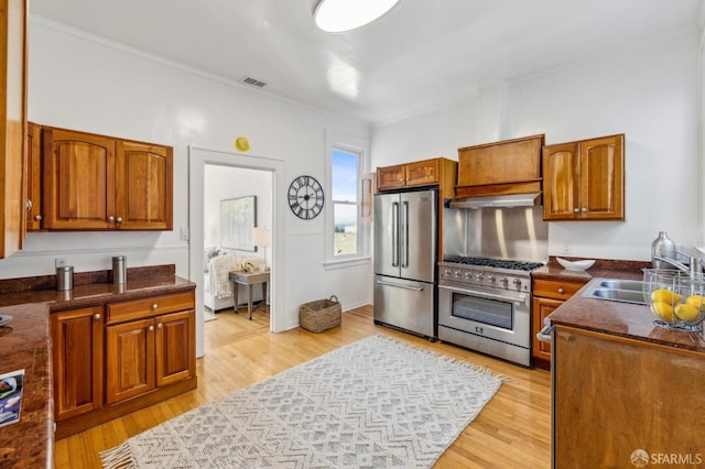 1015 Ashbury St Unit 4, San Francisco, CA 94117 - kitchen with stainless steel appliances, ornamental molding, brown cabinets, light wood-style floors, and under cabinet range hood