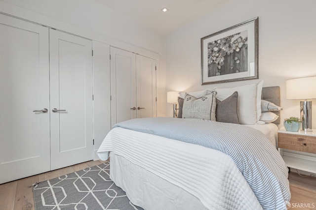 bedroom with recessed lighting, wood finished floors, and two closets