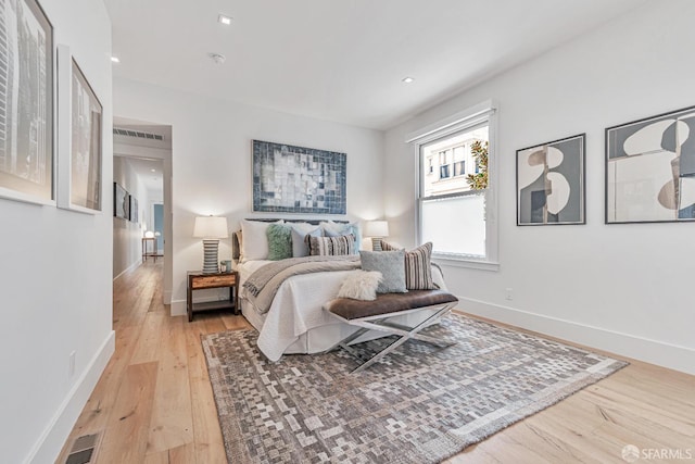 bedroom with visible vents, light wood-style flooring, and baseboards