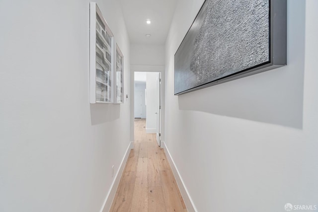 corridor with baseboards and light wood-style flooring