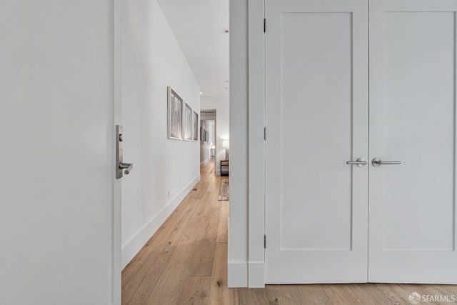 corridor featuring light wood-style flooring and baseboards