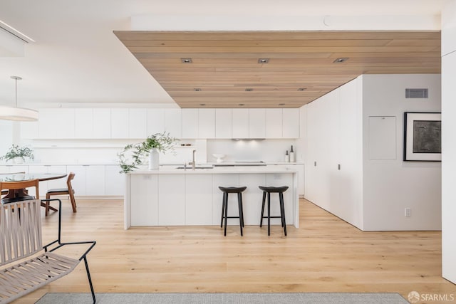 38 Bryant St Unit 405, San Francisco, CA 94105 - kitchen with white cabinetry, a kitchen island with sink, a kitchen bar, hanging light fixtures, and modern cabinets