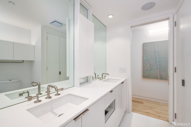 38 Bryant St Unit 405, San Francisco, CA 94105 - full bathroom with double vanity, wood finished floors, toilet, and recessed lighting
