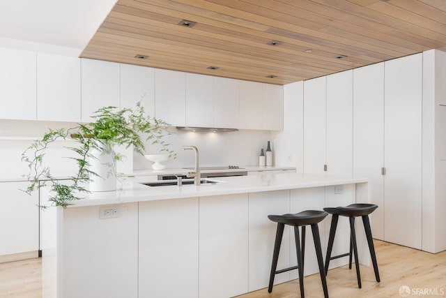 38 Bryant St Unit 405, San Francisco, CA 94105 - kitchen featuring a sink, light countertops, wood ceiling, white cabinetry, and light wood-type flooring