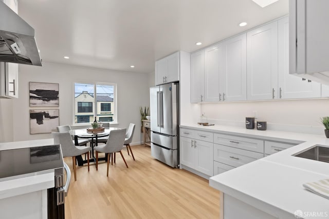 1727 45th Ave, San Francisco, CA 94122 - kitchen with freestanding refrigerator, wall chimney exhaust hood, light wood-style flooring, light countertops, and white cabinets