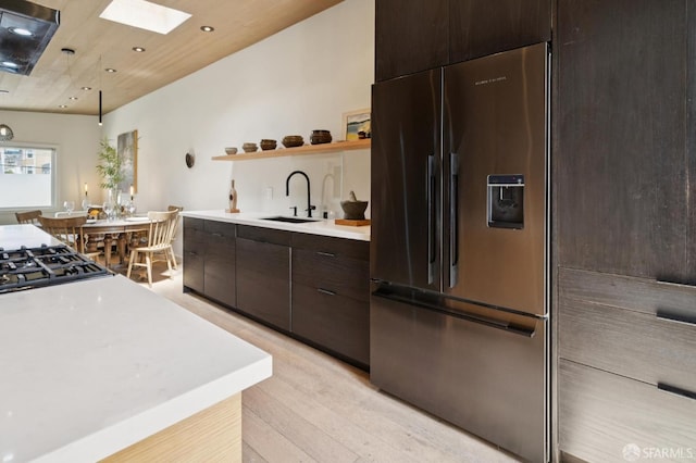 1515 Van Dyke Ave, San Francisco, CA 94124 - kitchen with high end fridge, light wood-style floors, light countertops, a skylight, and dark brown cabinets