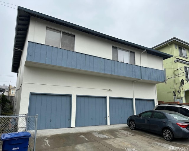 exterior space with fence, an attached garage, driveway, and stucco siding
