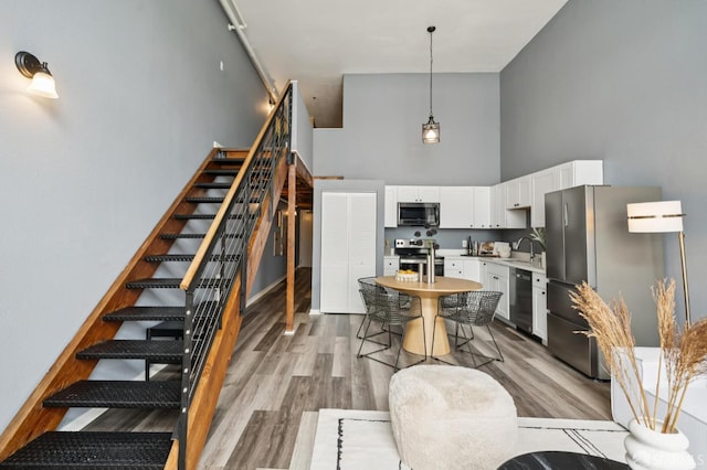 175 Bluxome St Unit 202, San Francisco, CA 94107 - kitchen featuring appliances with stainless steel finishes, a high ceiling, light countertops, white cabinetry, and light wood-style floors