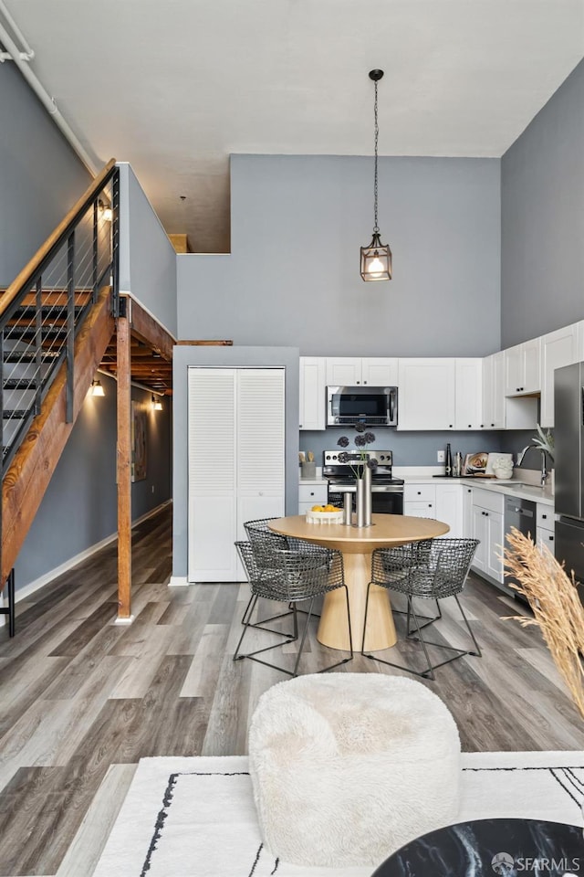 175 Bluxome St Unit 202, San Francisco, CA 94107 - kitchen with appliances with stainless steel finishes, a high ceiling, light countertops, white cabinets, and wood finished floors