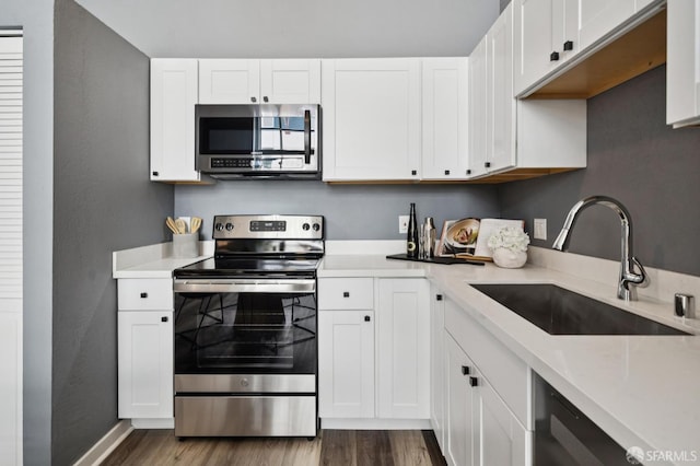 175 Bluxome St Unit 202, San Francisco, CA 94107 - kitchen featuring appliances with stainless steel finishes, dark wood-style flooring, light countertops, and white cabinetry