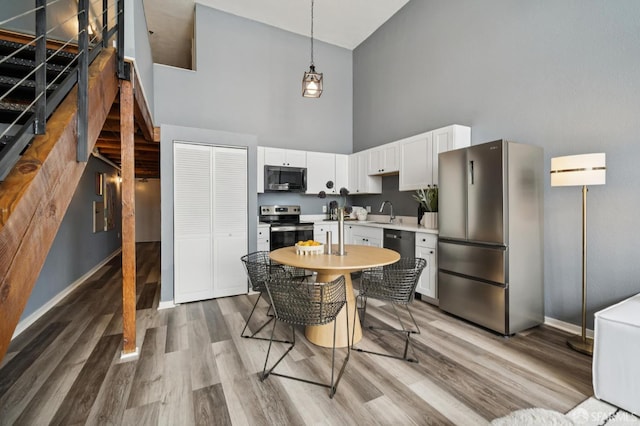 175 Bluxome St Unit 202, San Francisco, CA 94107 - kitchen featuring stainless steel appliances, a towering ceiling, light countertops, light wood-style floors, and white cabinets
