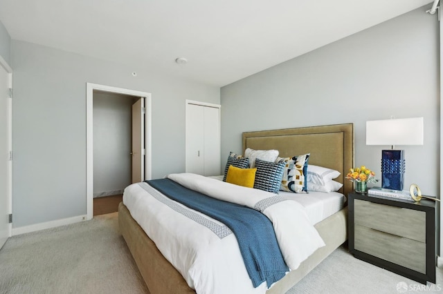 bedroom featuring baseboards, light colored carpet, and a closet
