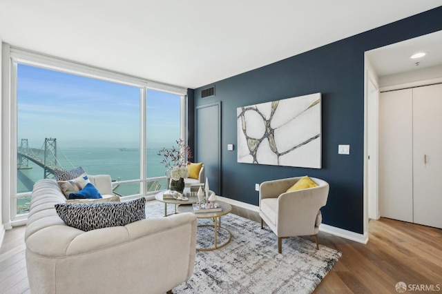 living area with visible vents, baseboards, a water view, and wood finished floors