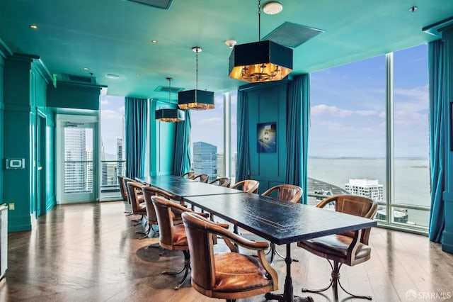 dining room featuring a wall of windows, a water view, and hardwood / wood-style flooring
