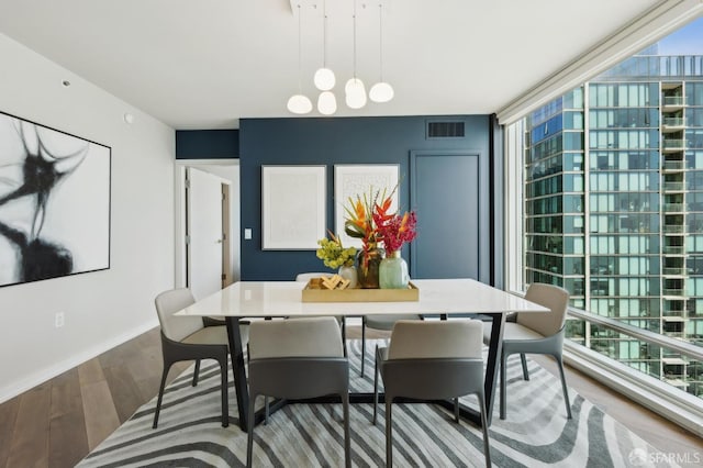 dining area with a healthy amount of sunlight, baseboards, wood finished floors, and visible vents