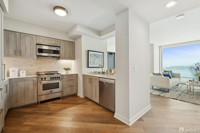 kitchen with light countertops, appliances with stainless steel finishes, decorative backsplash, and wood-type flooring