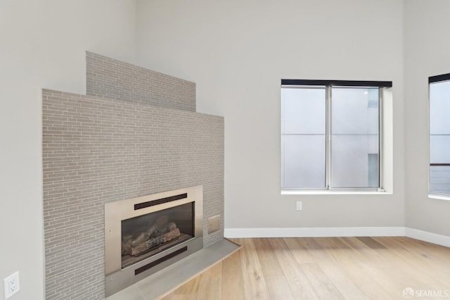 unfurnished living room with a high ceiling and light wood-type flooring