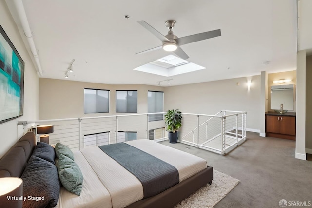 carpeted bedroom with track lighting, ceiling fan, and a skylight