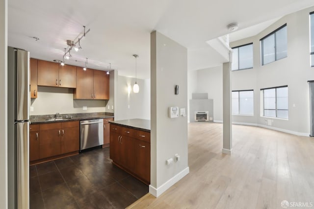 kitchen featuring appliances with stainless steel finishes, hardwood / wood-style floors, sink, hanging light fixtures, and track lighting