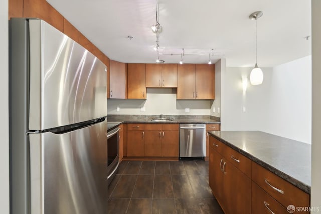 kitchen featuring sink, appliances with stainless steel finishes, dark tile patterned flooring, decorative light fixtures, and dark stone counters