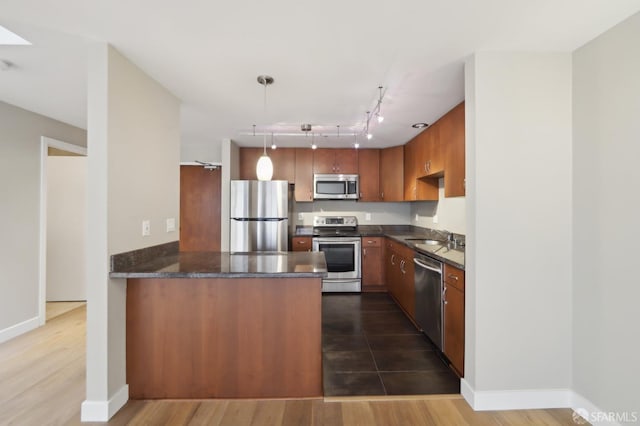 kitchen featuring sink, hanging light fixtures, stainless steel appliances, dark hardwood / wood-style flooring, and kitchen peninsula