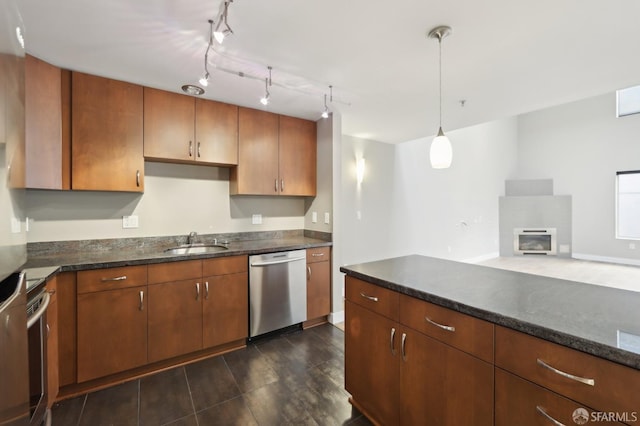 kitchen featuring stainless steel appliances, decorative light fixtures, sink, and dark stone countertops