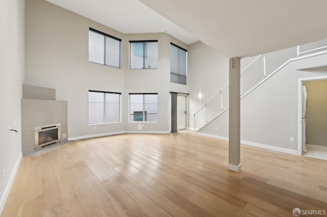 unfurnished living room featuring light hardwood / wood-style floors and a high ceiling