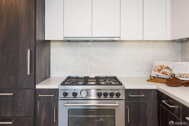 kitchen featuring stainless steel range, decorative backsplash, white cabinetry, and extractor fan