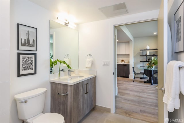 bathroom featuring wood-type flooring, vanity, and toilet