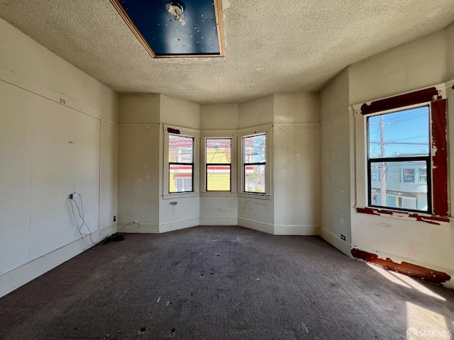 carpeted spare room with a textured ceiling