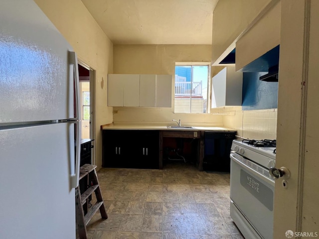 kitchen featuring white appliances, a sink, stone finish flooring, light countertops, and white cabinets