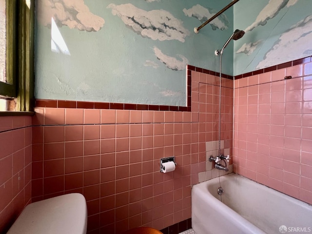 full bath with tile walls, toilet, shower / washtub combination, and a wainscoted wall