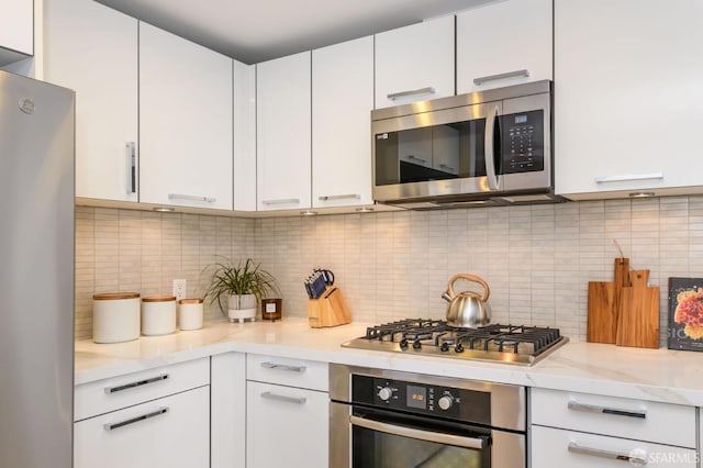 kitchen with backsplash, white cabinetry, light stone countertops, and stainless steel appliances