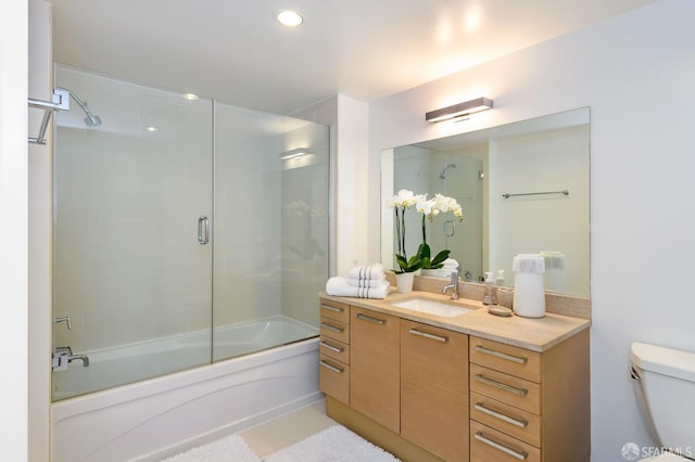 full bathroom featuring vanity, enclosed tub / shower combo, and toilet