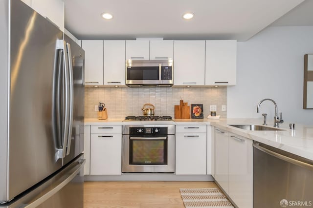 kitchen with white cabinets, backsplash, stainless steel appliances, and sink