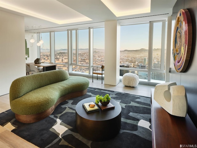 interior space with wood finished floors, floor to ceiling windows, a tray ceiling, a chandelier, and a mountain view