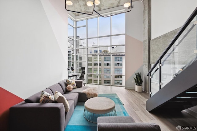 living room with a high ceiling, light hardwood / wood-style flooring, and a wall of windows