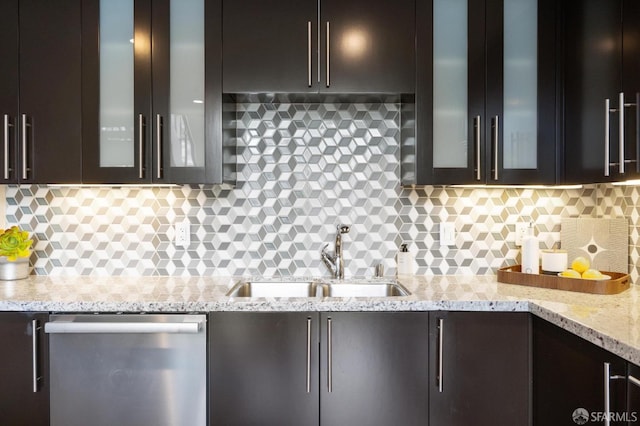 kitchen with sink, stainless steel dishwasher, decorative backsplash, light stone countertops, and dark brown cabinets