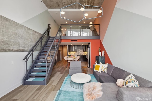 living room featuring a chandelier, a towering ceiling, and wood-type flooring