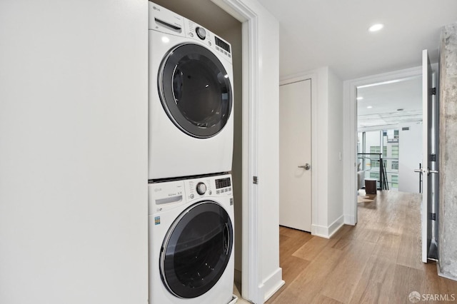 laundry area with stacked washer and clothes dryer and light wood-type flooring