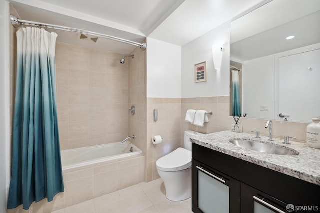 full bathroom featuring tile patterned flooring, toilet, shower / bath combo with shower curtain, vanity, and tile walls