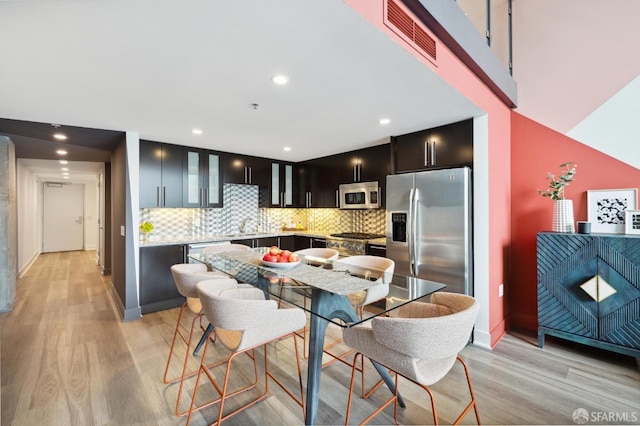 kitchen with decorative backsplash, light wood-type flooring, stainless steel appliances, and sink