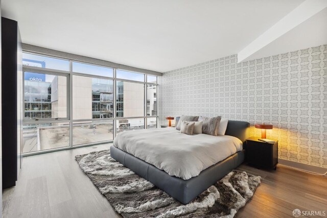 bedroom with a wall of windows and hardwood / wood-style flooring