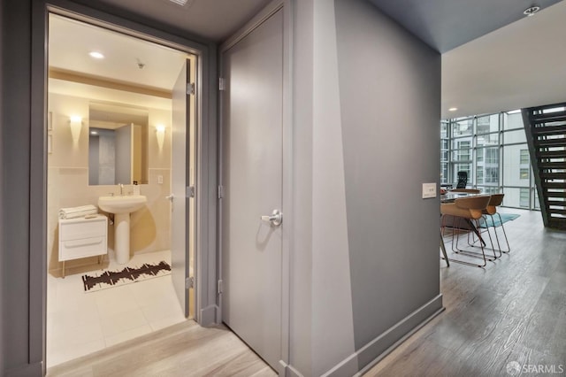 corridor featuring floor to ceiling windows, sink, and hardwood / wood-style flooring