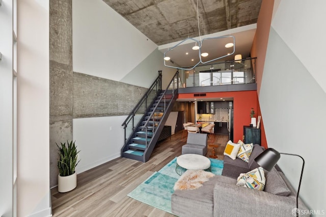 living room featuring hardwood / wood-style flooring, a notable chandelier, and a high ceiling