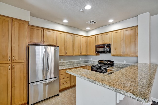 kitchen featuring black appliances, a peninsula, recessed lighting, light stone counters, and a textured ceiling