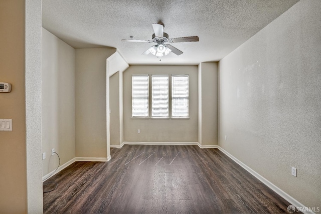 empty room with dark wood-style flooring, ceiling fan, baseboards, and a textured ceiling